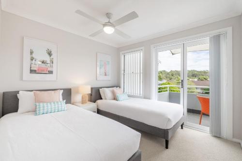 a bedroom with two beds and a balcony at Sandcastles 1, 8 Ala Moana Way - air conditioned townhouse with Wi-Fi and Complex Pool in Fingal Bay