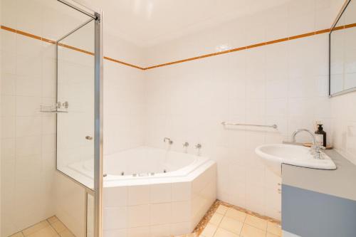 a white bathroom with a tub and a sink at Sandcastles 1, 8 Ala Moana Way - air conditioned townhouse with Wi-Fi and Complex Pool in Fingal Bay