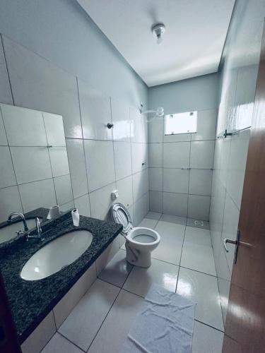 a white bathroom with a sink and a toilet at Aconchego e praticidade in Mineiros