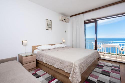 a bedroom with a bed and a view of the ocean at Apartments Vedra in Baška Voda