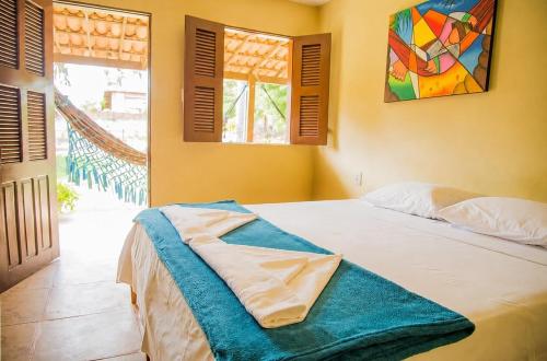 a bedroom with a bed with a painting on the wall at Eco Hostal Yuaiurú in Trairi