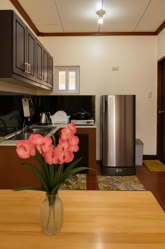 a vase with pink flowers on a table in a kitchen at Audi's Serviced Apartment in Puerto Princesa City