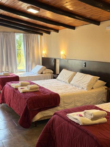 a hotel room with three beds with towels on them at Posada Bambys in Concordia