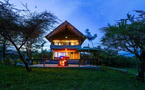 a building with a deck with lights in the night at Kitumo Mara Lodges in Mara Simba