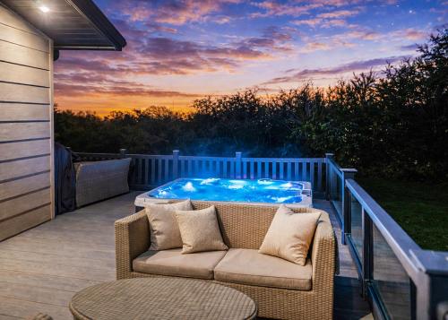 a hot tub sitting on a deck with a couch at Foxhunter Park in Kent