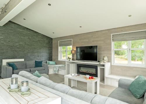 a living room with a couch and a fireplace at Aspen Lodge Escape in Hengrave