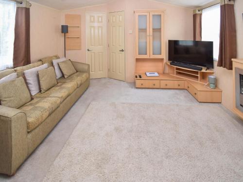 a living room with a couch and a flat screen tv at Fellside Lodge in Cockermouth