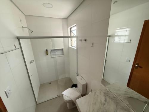 a white bathroom with a shower and a toilet at POUSADA MILÊNIO LTDA in Ponte Nova