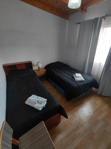 a bedroom with two beds and a table and a window at Refugio del Viento in Gobernador Gregores