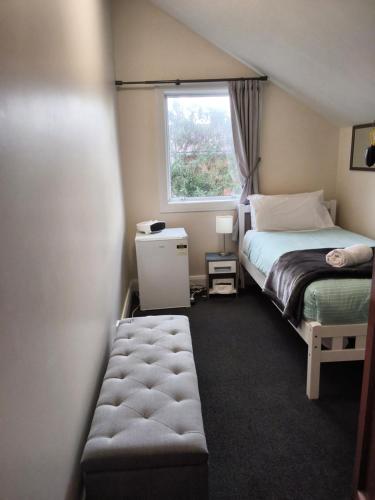 a small bedroom with a bed and a window at North Beach Lodge in Christchurch