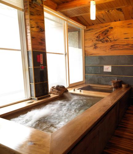 a jacuzzi tub in a wooden room with windows at Sun Moon Bed& Breakfast 日月民宿 in Wulai