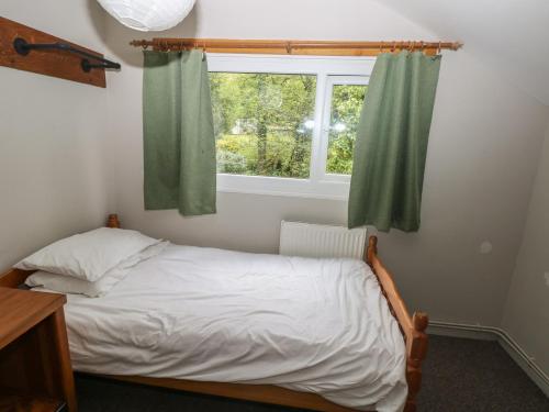 a small bedroom with a bed and a window at Cabin No 3 - Salt and Fern Cabins in Port Talbot