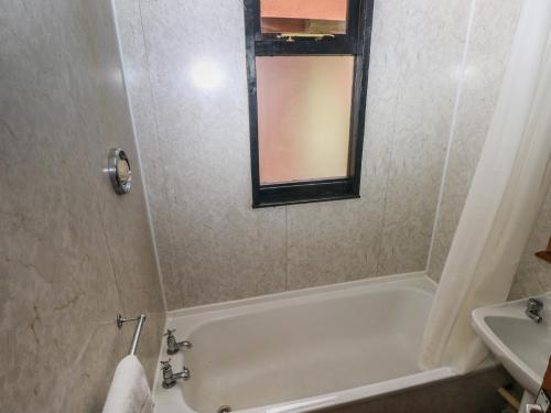 a bathroom with a bath tub and a sink at Cabin No 3 - Salt and Fern Cabins in Port Talbot
