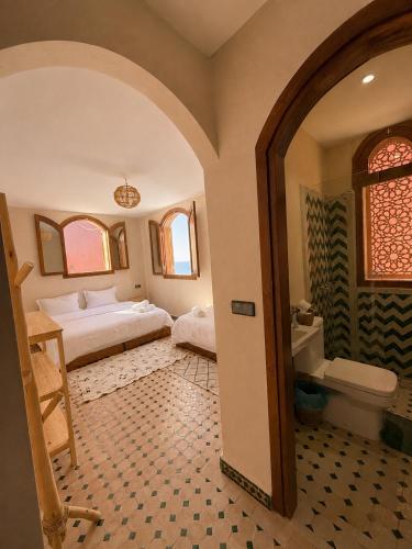 a bedroom with two beds and a bathroom with a tub at Kymata Surf Morocco in Agadir