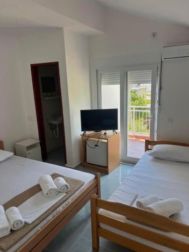a bedroom with two beds and a television and a balcony at Navora Apartmani in Sutomore