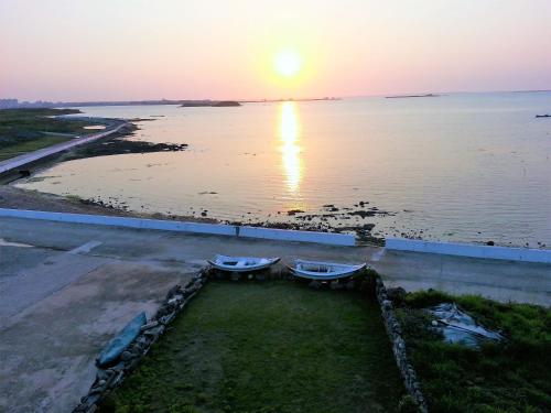 two boats sitting on the grass near the water at sunset at Ocean Sky B&B in Huxi