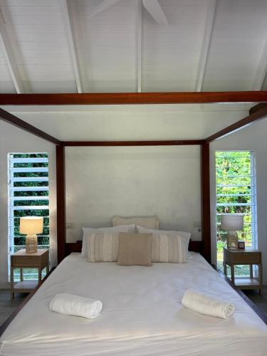 a bedroom with a large white bed with two pillows at Coconut Beach House & Cottages in Cape Tribulation