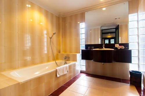 a bathroom with a tub and a sink and a mirror at Champlung Mas Hotel Legian in Legian