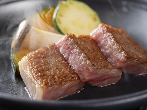 a plate with three pieces of meat and a pickle at Wan Wan Paradise Takayama in Takayama