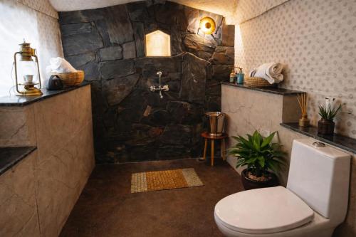 a bathroom with a toilet and a stone wall at The Stone Hamlet Retreat in Barkot