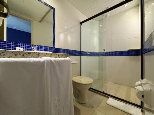 a bathroom with a toilet and a glass shower at Center Verdes Pássaros Loft in Porto Alegre