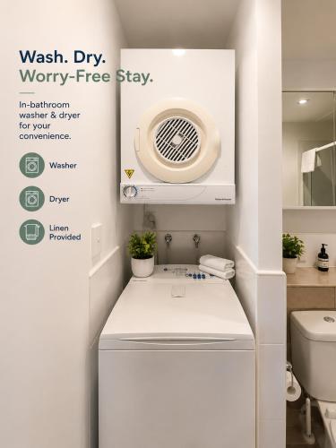 a bathroom with a washing machine in a room at Quest on Queen Serviced Apartments in Auckland