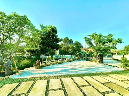 a walkway in a park with trees and a bridge at รักแรกพบรีสอร์ทสัตหีบ in Sattahip