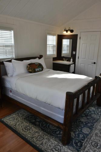 a bedroom with a large white bed and a bathroom at Tiny Yellowstone Riverside Cabin in Gardiner