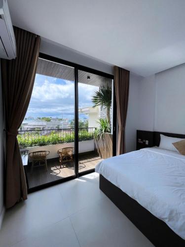 a bedroom with a bed and a view of a balcony at The SeaNest Home - Làng Chài Mỹ Tân Ninh Thuận in Vinh Hai