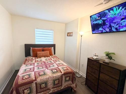 a bedroom with a bed and a flat screen tv on the wall at Disney Kissimmee Condo in Kissimmee