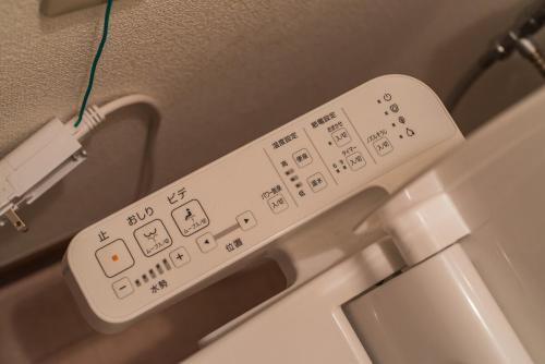 a white remote control sitting on top of an appliance at 3 min from the station in Tokyo