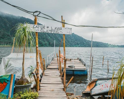 a dock on a lake with a sign on it at Catur Glamping Bedugul in Bedugul