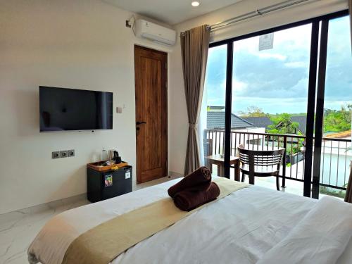 a bedroom with a large bed and a balcony at Sekar Uluwatu in Uluwatu