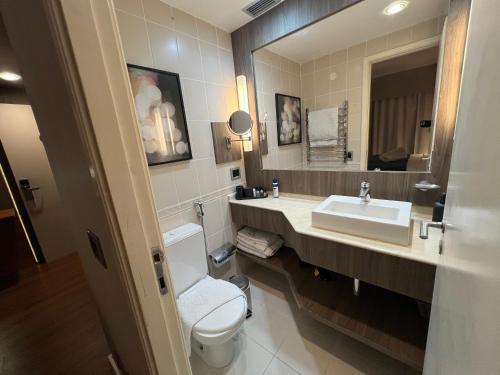 a bathroom with a sink and a toilet and a mirror at Apart Hotel Itaim Bibi in São Paulo
