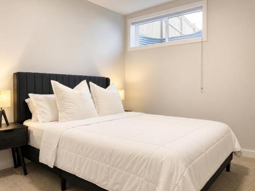 a bedroom with a large white bed with a window at Modern 2BR Private Suite in SW Calgary in Calgary