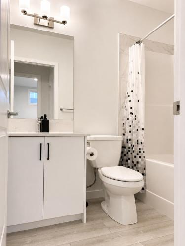 a white bathroom with a toilet and a shower at Modern 2BR Private Suite in SW Calgary in Calgary