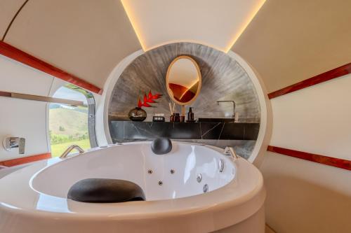 eine runde Badewanne in einem Raum mit einem runden Spiegel in der Unterkunft Pousada Aero Sofiste in Divino de São Lourenço