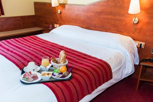 a tray of food on a bed in a hotel room at CIT'HOTEL Armony Hotel in Bourg-Achard