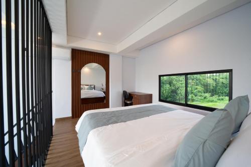 a bedroom with a large bed and a large window at Lunaire Guest House in Tabanan