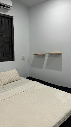 a white room with two beds and a shelf on the wall at Nồm House in Nha Trang