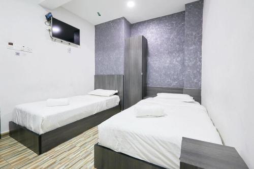 a room with two beds and a tv on a wall at Fast Hotel Idaman Near To IIUM KL in Kuala Lumpur