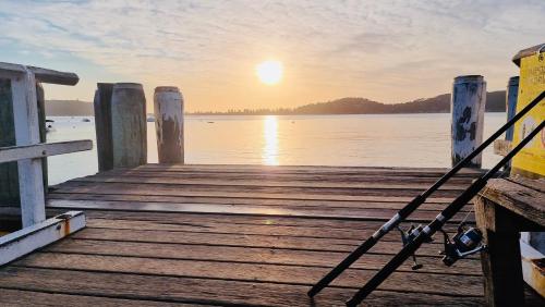 a camera on a dock with the sun setting over the water at Mackerel Beach Wellness Lodge in Great Mackerel Beach