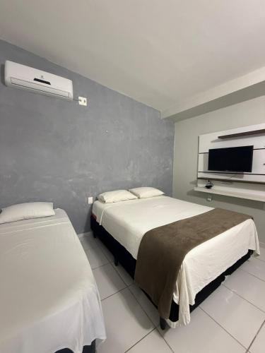 a bedroom with two beds and a flat screen tv at Suíte Brisa Mar Villa brisa icaraizinho in Amontada