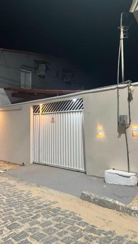 a white building with a white gate at night at Suíte Brisa Mar Villa brisa icaraizinho in Amontada