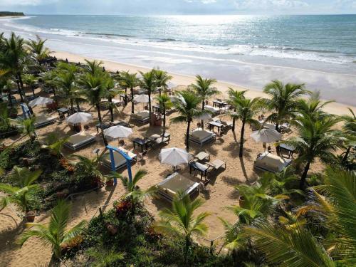an aerial view of a beach with palm trees and umbrellas at AWÊ Villa Boutique & Beach Club in Trancoso