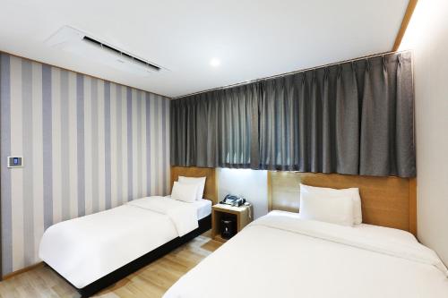 two beds in a hotel room with curtains at Paju Golden Hill in Paju