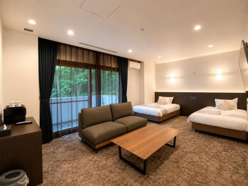 a hotel room with a couch and a bed at LiVEMAX Golf Club Tochigi in Kanuma