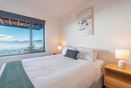 a bedroom with a large bed and a large window at Rosetta Vista - Architectural Haven with River Views in Berriedale