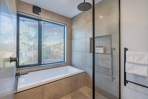 a bathroom with a bath tub and a window at Rosetta Vista - Architectural Haven with River Views in Berriedale