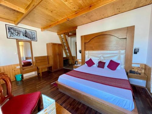 a bedroom with a large bed with red pillows at Hotel The Red Apple in Manāli
